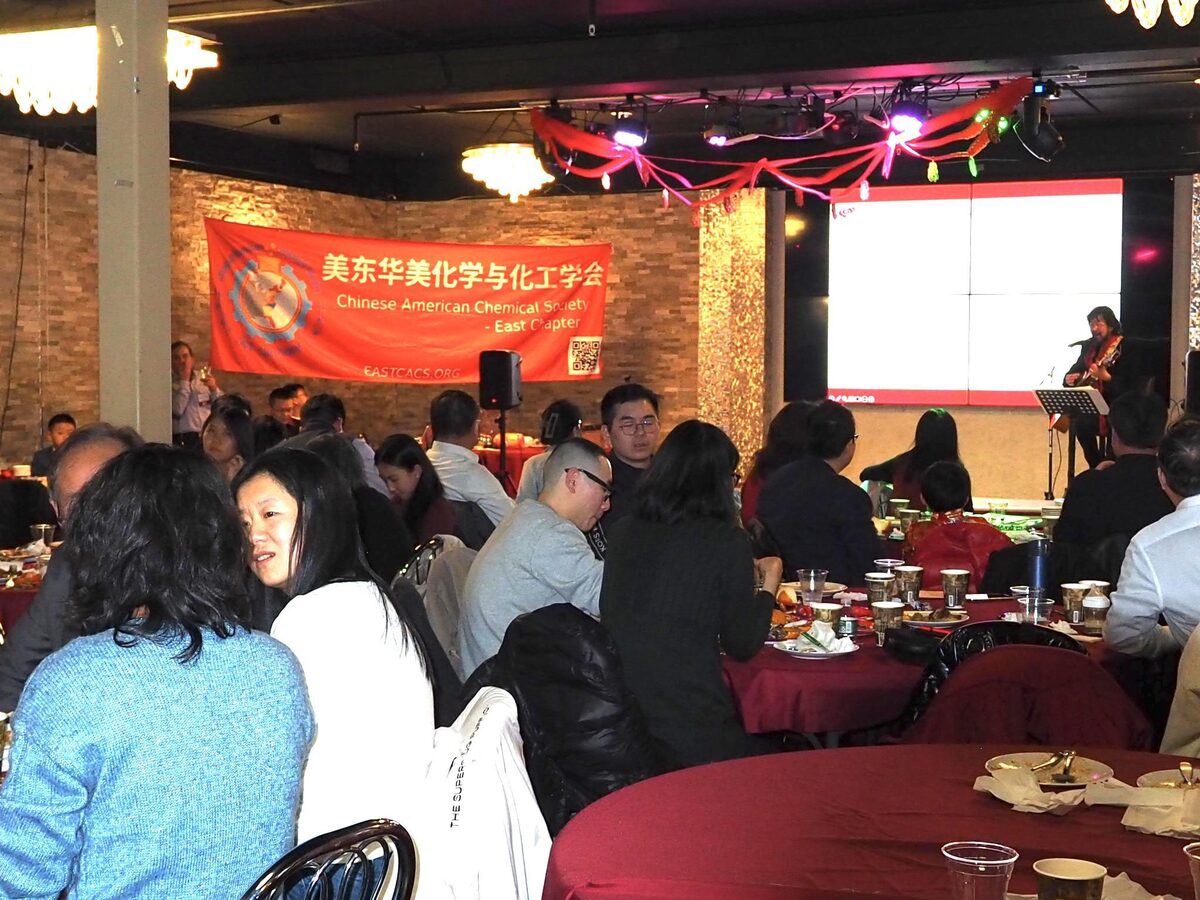 E-CACS Chinese New Year party — attendees seated for dinner with the society's red banner on stage