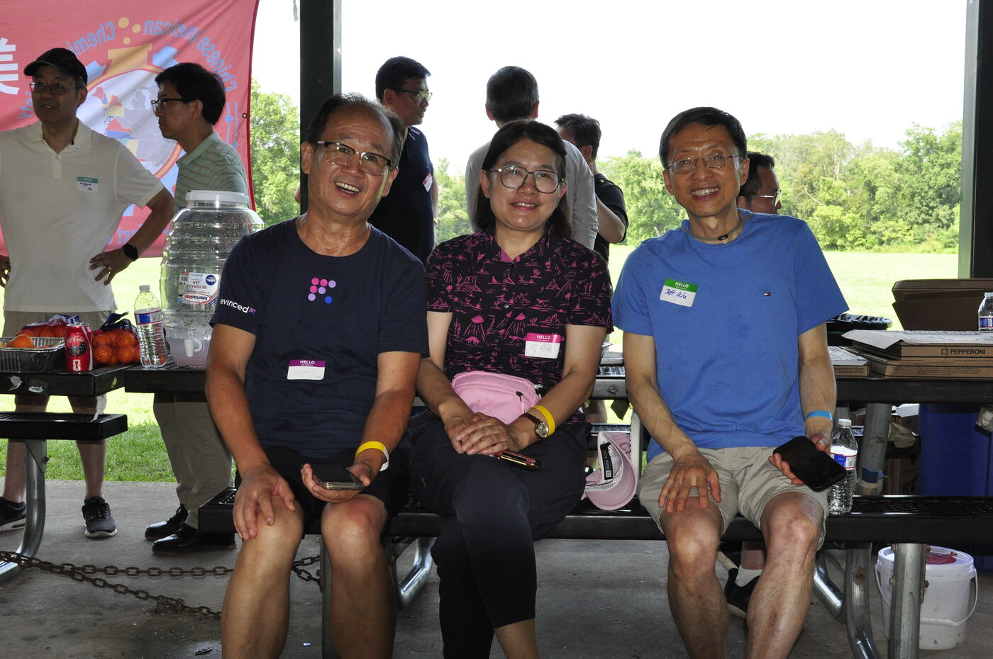 Three attendees seated together on a picnic bench.