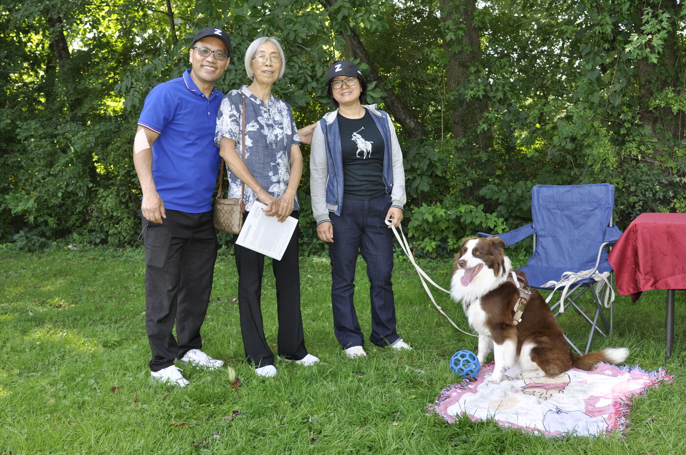 A family with their dog on the lawn at the picnic.