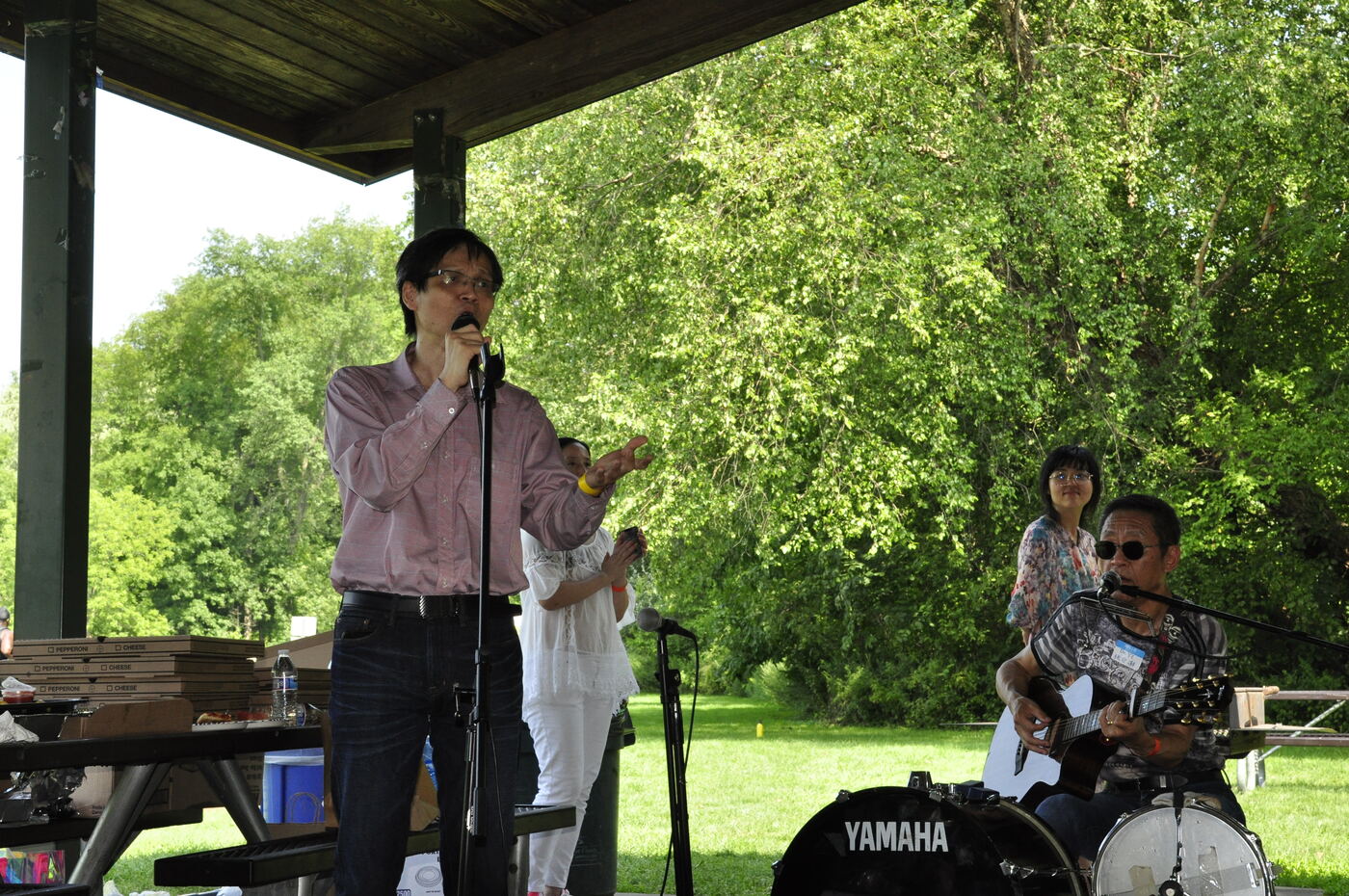 A performer singing with accompaniment under the pavilion.