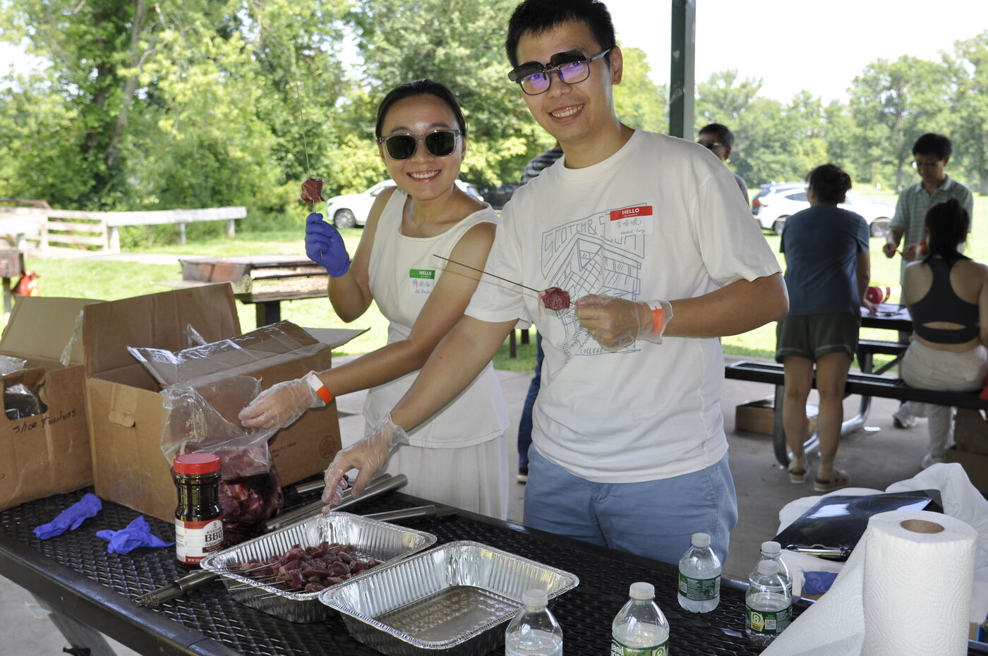Two attendees preparing trays of food at the grill table.