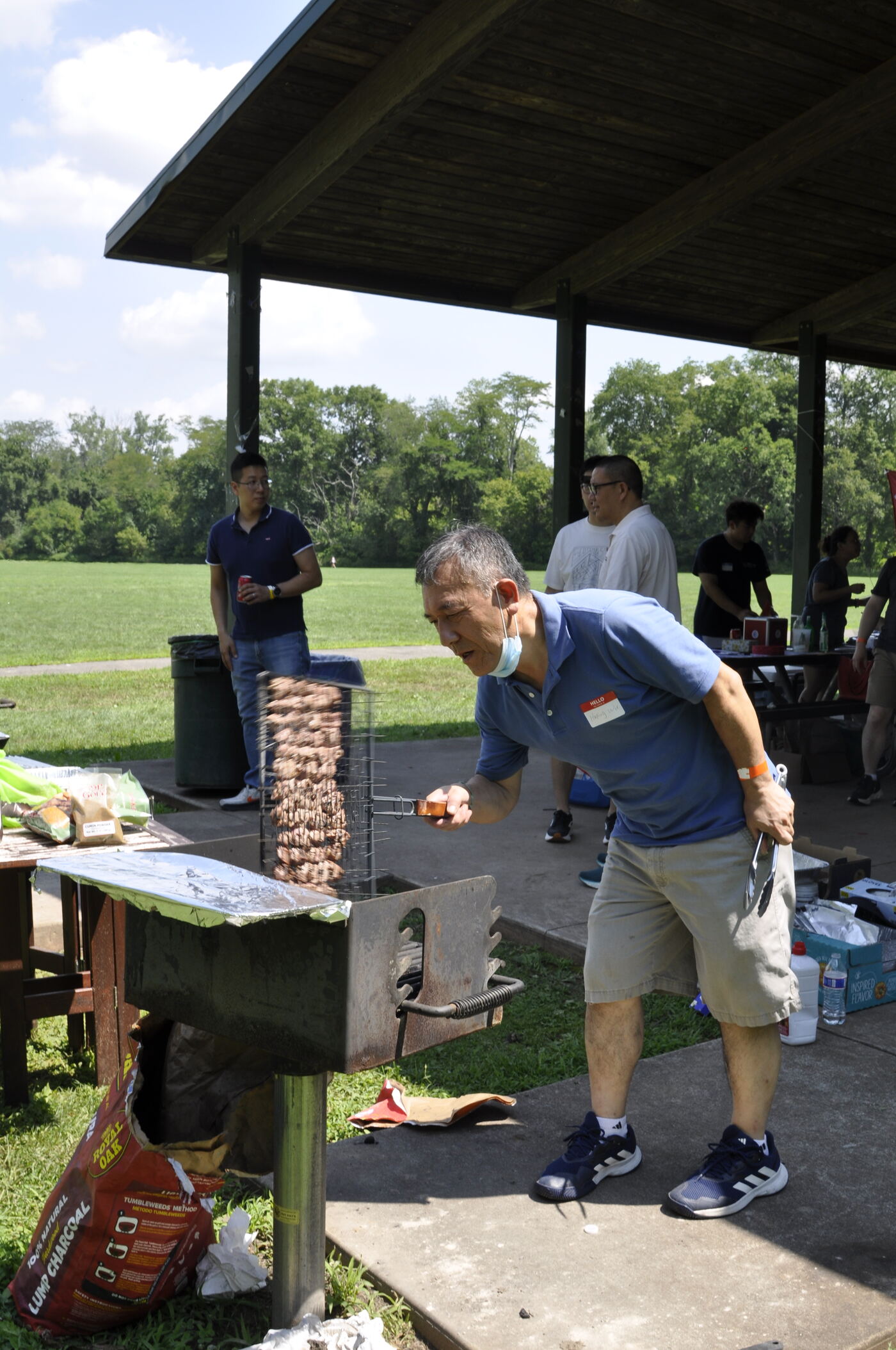 A volunteer tending rows of skewers on a vertical grill.