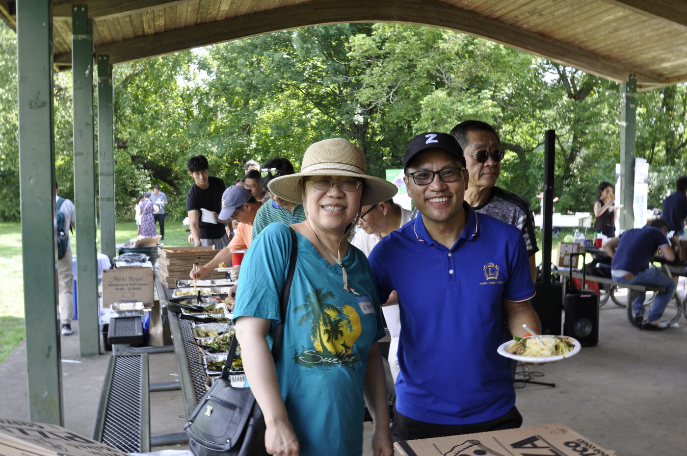 Two attendees with plates of food under the pavilion.