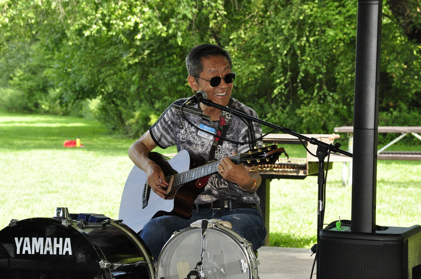 A performer playing acoustic guitar beside the drum kit.