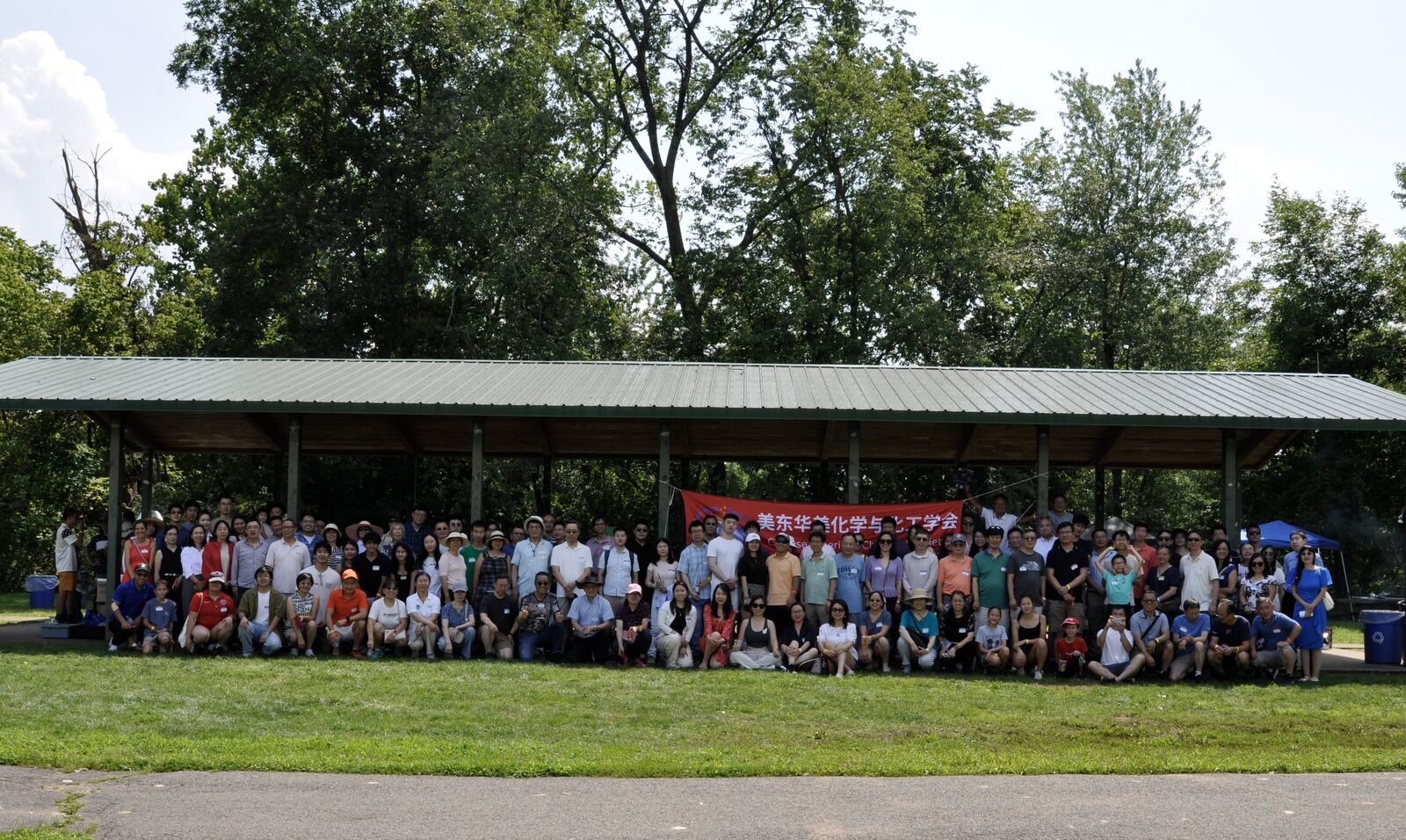 Wide group photo of all 2026 Summer BBQ Picnic attendees lined up along the park pavilion.
