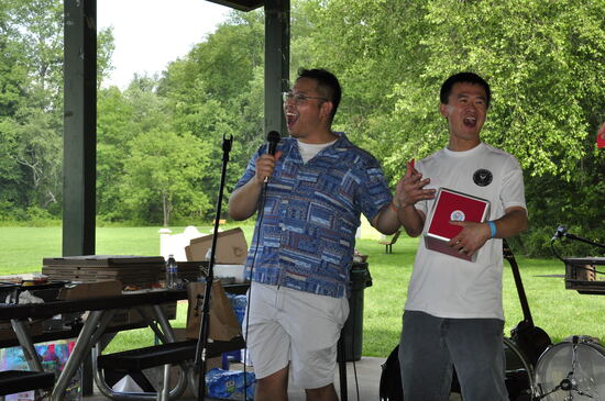 Two attendees with an award plaque at the microphone.